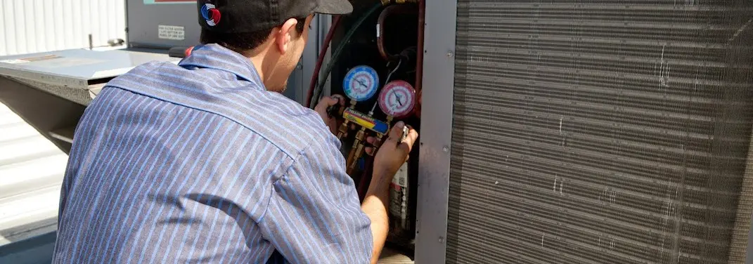 HVAC technician servicing a condenser unit in El Campo